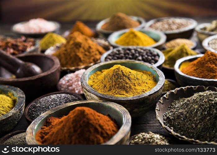Spice Still Life, wooden bowl. A selection of various colorful spices on a wooden table in bowls