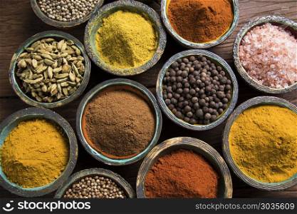 Spice Still Life, wooden bowl. A selection of various colorful spices on a wooden table in bowls