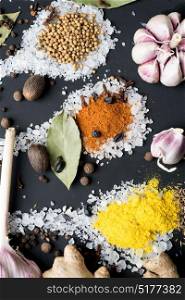 Spices and seeds in salt spoon at black background. seasoning. Colorful natural additives.