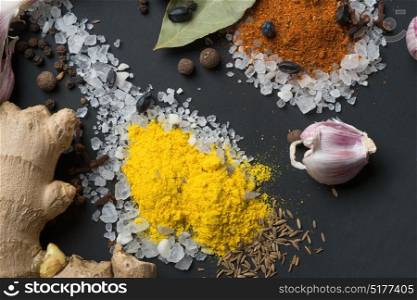 Spices and seeds in salt spoon at black background. seasoning. Colorful natural additives.