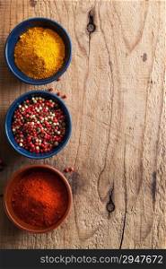 spices background: pink and black pepper, paprika powder, curry