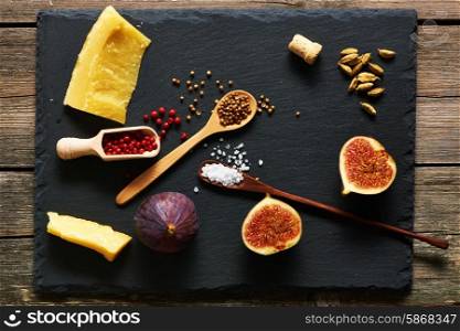 Spices, cheese and figs over slate
