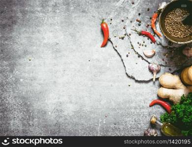 Spices in a mortar with ginger and herbs. On a stone background.. Spices in a mortar with ginger and herbs