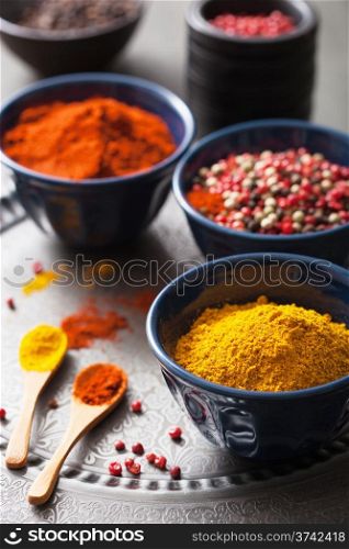 spices in bowls: curry, pink and black pepper, paprika powder