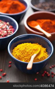 spices in bowls: curry, pink and black pepper, paprika powder