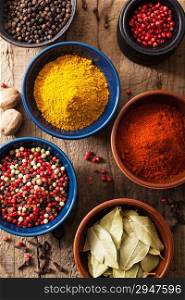 spices in bowls: pink black pepper, paprika powder, curry, bay leaf