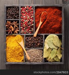 spices in box pink and black pepper, paprika powder, curry, bay leaf, anise, clove, cumin