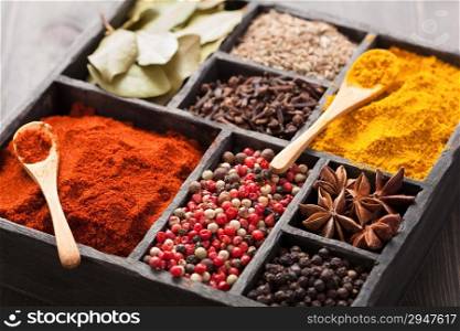 spices in box: pink and black pepper, paprika powder, curry, bay leaf; anise; clove; cumin