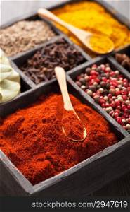 spices in box: pink black pepper, paprika powder, curry, bay leaf; anise; clove; cumin