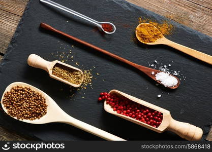 Spices in wooden utensils over slate