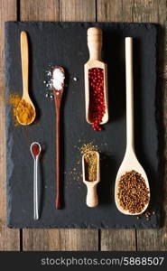 Spices in wooden utensils over slate