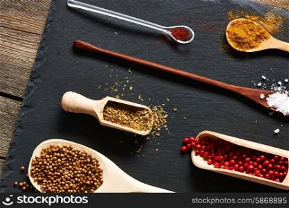 Spices in wooden utensils over slate