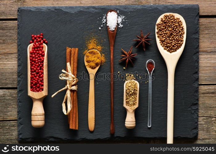 Spices in wooden utensils over slate