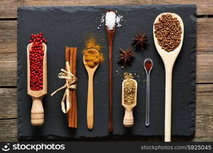 Spices in wooden utensils over slate