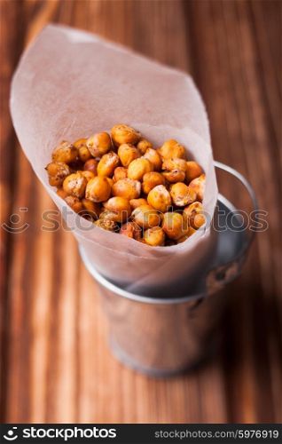 Spicy baked chickpeas in a metal pail on the wooden background. Spicy baked chickpeas