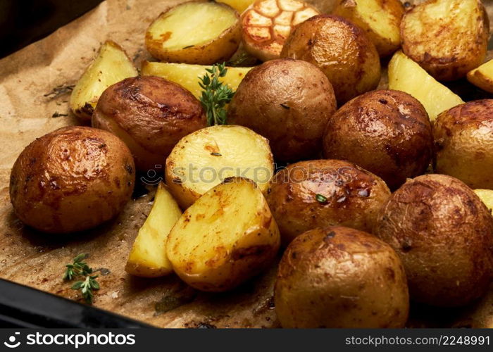 Spicy baked potato in tray with rosemary and garlic on parchment layer. High quality photo. Spicy baked potato in tray with rosemary and garlic on parchment layer