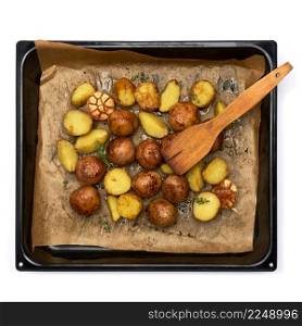 Spicy baked potato in tray with rosemary and garlic on parchment layer. High quality photo. Spicy baked potato in tray with rosemary and garlic on parchment layer