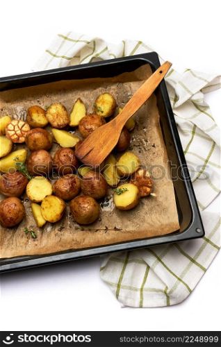 Spicy baked potato in tray with rosemary and garlic on parchment layer. High quality photo. Spicy baked potato in tray with rosemary and garlic on parchment layer