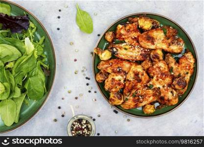Spicy chicken wings with vegetables and green salad. Top view. Grilled chicken wings.