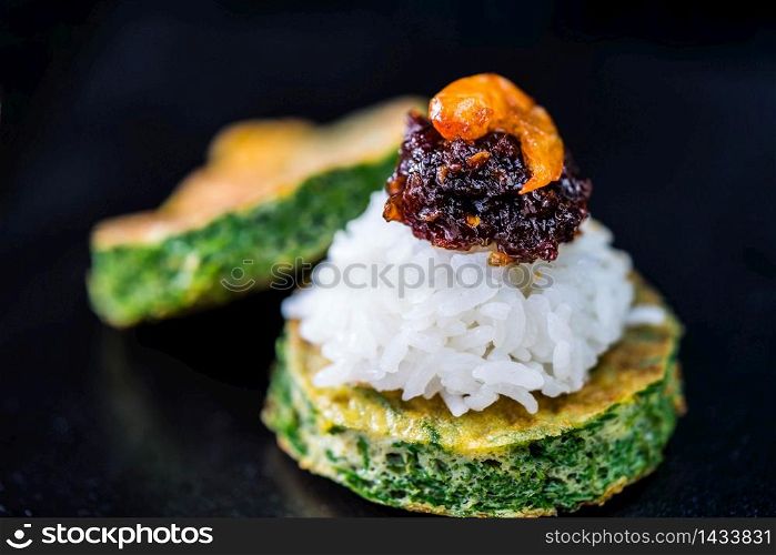 Spicy chili paste with steamed rice and fried Egg with Climbing Wattle on dark background