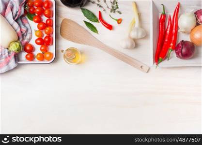 Spicy cooking. Various spices, olive oil, chili, onion, garlic and Bay leaves with cooking spoon on white wooden background, top view, border. Healthy food concept