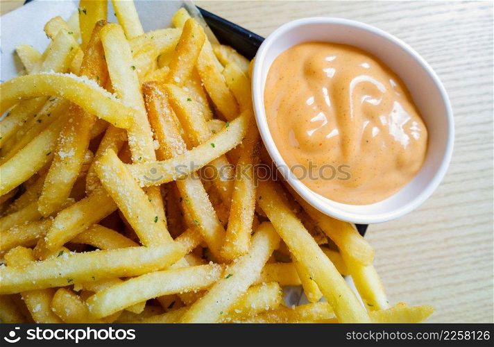 spicy french fries on tracing paper on board on wooden table