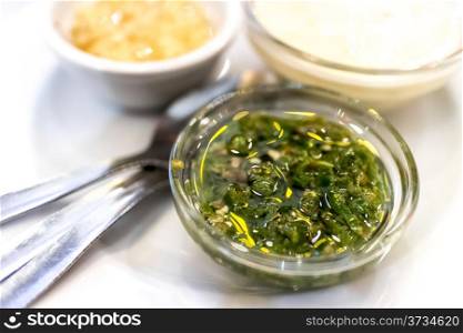 Spicy green pepper condiment served in a small bowl along with ranch and garlic sauce