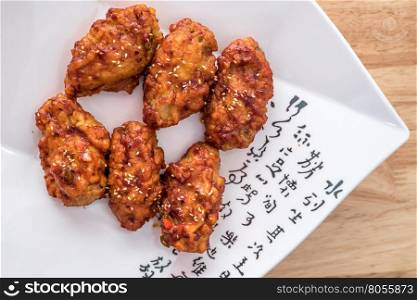 Spicy korean fried chicken with sesame on a plate