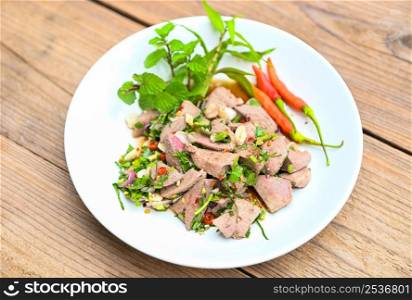 Spicy liver salad on white plate wooden table background, Pork liver salad with fresh chili herbs, spices, Thai food