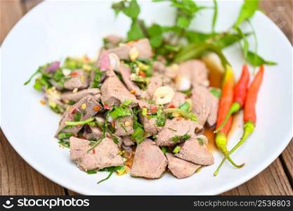 Spicy liver salad on white plate wooden table background, Pork liver salad with fresh chili herbs, spices, Thai food