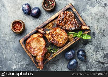 Spicy meat grilled spare ribs on wooden cutting board. Fried meat with plums