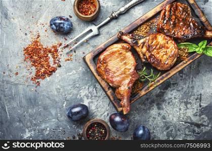 Spicy meat grilled spare ribs on wooden cutting board. Fried meat with plums