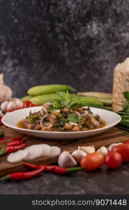 Spicy minced pork in a white plate with Tomatoes, garlic, long beans, sliced   shallots, chili powder, roasted rice.