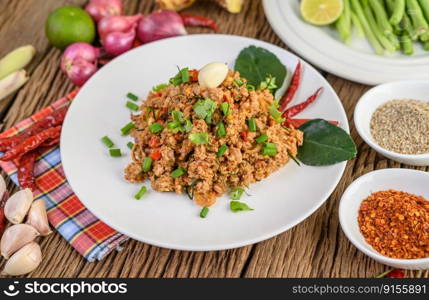 Spicy Minced Pork Salad on a white plate with red onion, lemon grass, garlic, yardlong beans, kaffir lime leaves, and spring onion