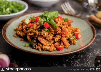 Spicy minced pork salad with chili flakes, lime, chopped green onions, chilli and roasted rice, sliced   shallots on a cement floor.