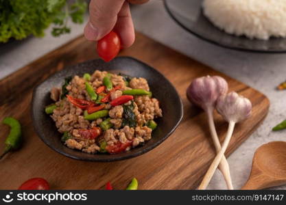 Spicy minced pork salad with rice, chilies, and tomatoes in a black plate.Selective focus.