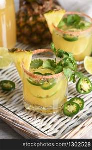 Spicy pineapple margarita with jalapeno slices, lime and cilantro sprigs