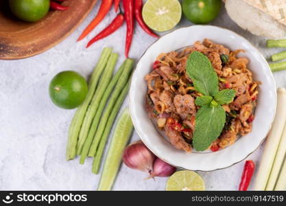 Spicy pork chops in a white dish consisting of lemons, chilies, and side dishes. Selective focus.