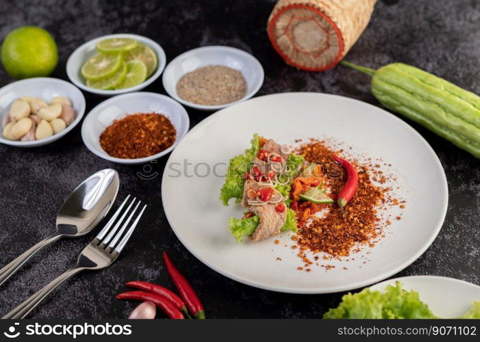 Spicy pork salad with galangal, lemon, chilli, garlic and put in a salad on a white plate.