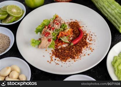 Spicy pork salad with galangal, lemon, chilli, garlic and put in a salad on a white plate.