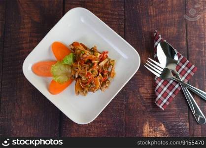 Spicy salad of sardine with tomato sauce mixed with herb in white dish and sparken stainless spoon and fork over napkin and cooking ingredient in weave basket on the wooden table, copy space