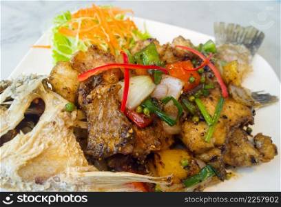 spicy sea bass fried with black pepper on white plate