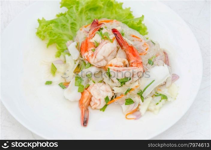 spicy seafood salad. spicy noodle salad with seafood on white dish