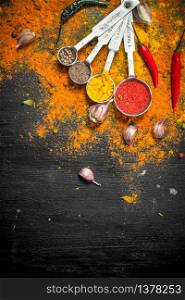 Spicy spices in measuring spoons. On the black chalkboard.. Spicy spices in measuring spoons.