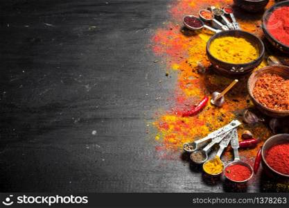 Spicy spices in measuring spoons. On the black chalkboard.. Spicy spices in measuring spoons.