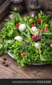 Spicy spring vegetable salad. Spring salad with rucola,tomatoes,mozzarella and berries of physalis