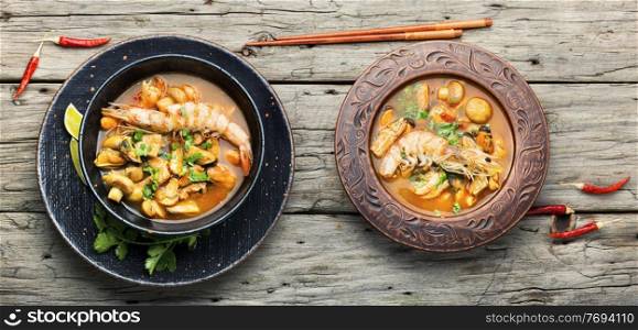Spicy thai soup tom yam in plate on rustic wooden background. Tom yum soup with seafood and coconut milk