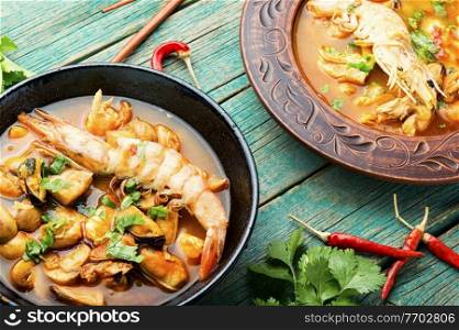 Spicy thai soup tom yam in plate on rustic wooden background. Tom yum soup with seafood and coconut milk