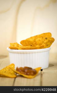 spicy tortilla chips and tomato salsa dip over wooden board