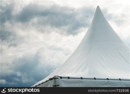 Spiked roof of white party event tent against sky with dark clouds.. Spiked roof of white party event tent